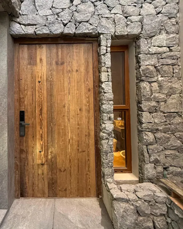 Puerta de pinotea de tabla entera colocada entre paredes de piedra