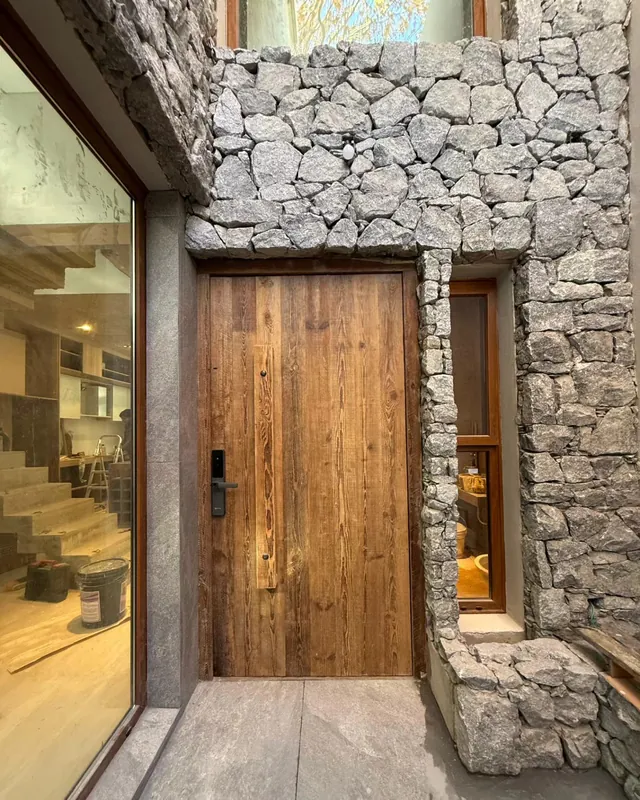 Puerta de pinotea de tabla entera en una pared de piedra